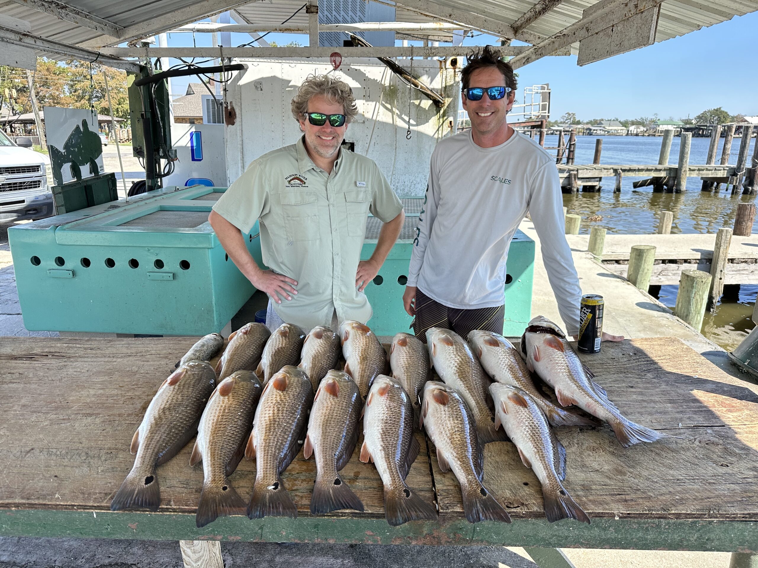 Two men showing off their redfish catch after a New Orleans fishing charter