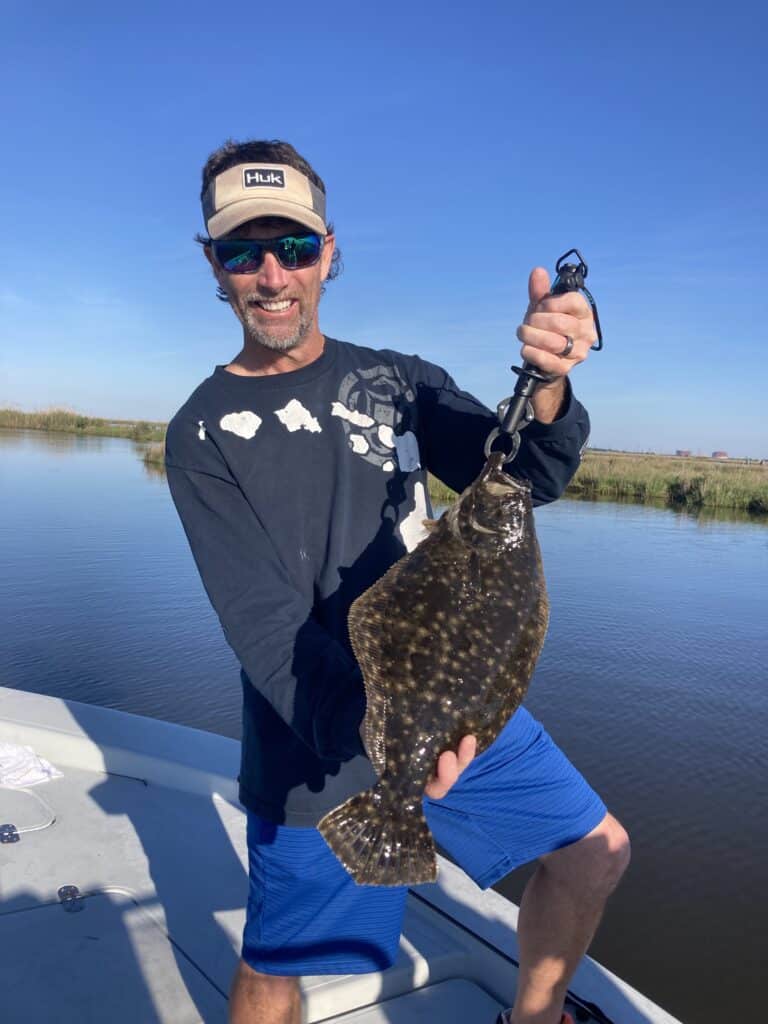 Man on a fishing boat in the bayou holding fish caught on a New Orleans Style Fishing Charter fishing trip