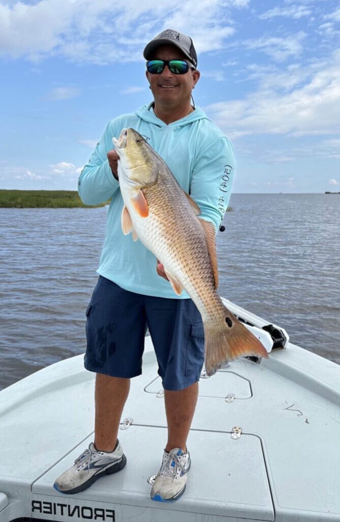 Owner of New Orleans Style Fishing Charters, Captain Jason Shilling, holding a redfish